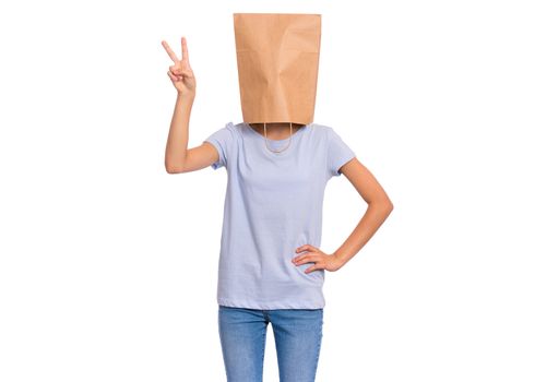 Portrait of teen girl with paper bag over head making Victory gesture. Teenager showing victory sign isolated on white background. Happy child posing in studio.