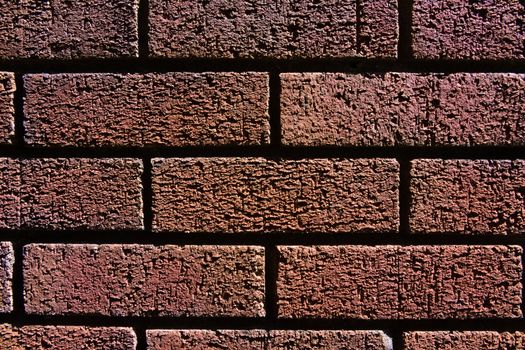 1 - Horizontal red brick wall background texture. Monochromatic appearance and dark shadows between the bricks.