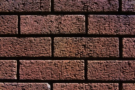 2 - Abstract texture close up of a red brick wall shadows and bright highlights make contrasted image. Fine grain and structure visible. Horizontal.