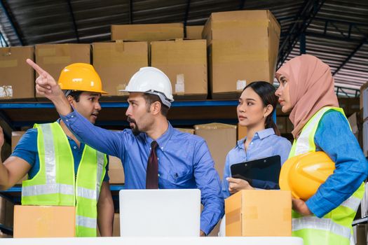 Group of Diversity warehouse worker meeting and brainstorming together in local warehouse, muslim with Hijab, indian, white caucasian and asian people wearing safety clothes in export industry concept