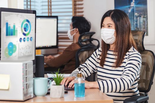 Couple of Asian colleagues wearing the surgical mask and working with computer in Home office when Covid-19 pandemic, Coronavirus outbreak,education and Social distancing,new normal concept