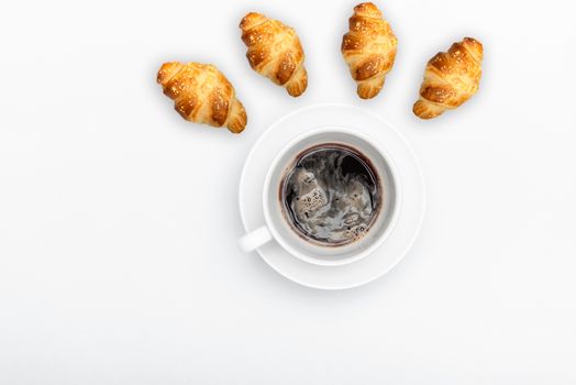 white cup with saucer and coffee on a white background with copyspace and french croissant