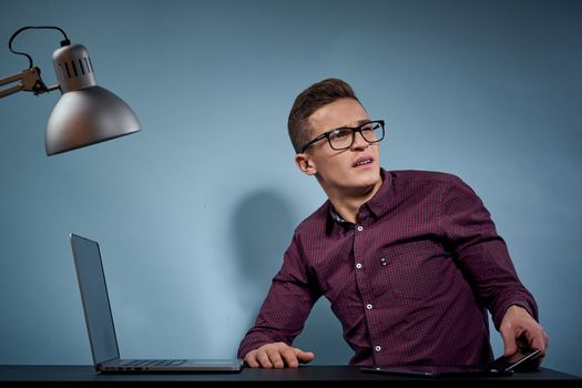 A man in a shirt with a laptop at the table is a manager in the office and a lamp cabinet model. High quality photo