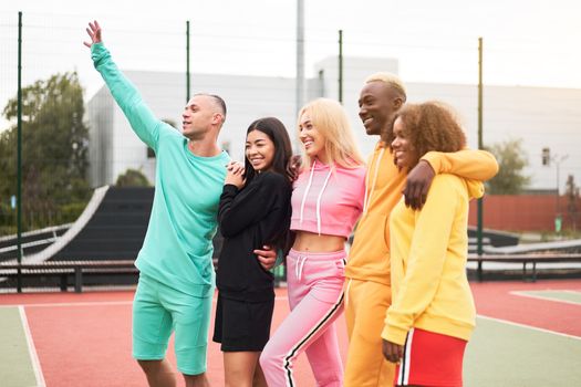 Multi-ethnic group teenage friends. African-american asian caucasian student spending time together Multiracial friendship Happy smiling People dressed colorful sportswear meeting outdoor sportground