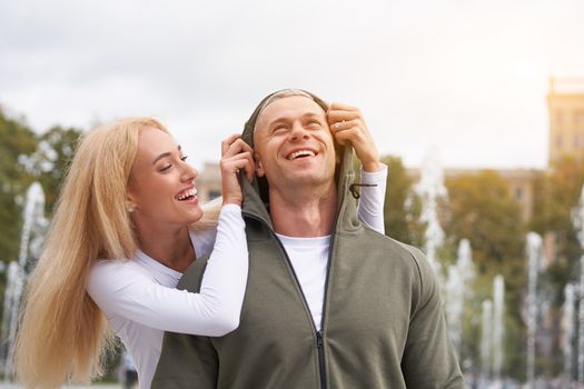 Couple in love walking outdoors park fountain Caucasian man woman walk outside after jogging dressed sport clothes Healthy livestyle dress up the hood