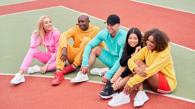 Multi-ethnic group teenage friends. African-american asian caucasian student spending time together Multiracial friendship Happy smiling People dressed colorful sportswear meeting outdoor sportground