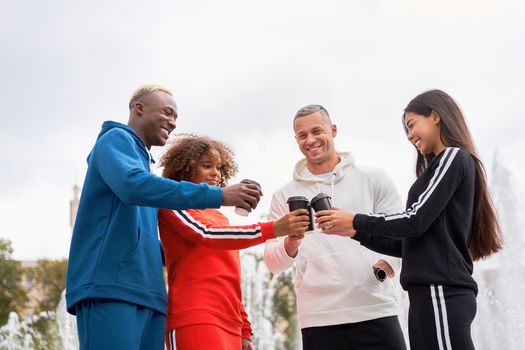 Multi-ethnic group teenage friends. African-american asian caucasian student spending time together Multiracial friendship Happy smiling People dressed colorful sportswear drink coffee outdoor
