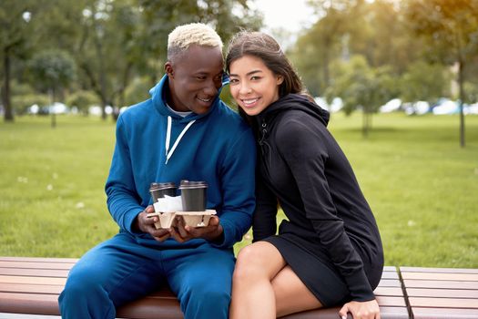 African american man proposes coffee asian woman Multiethnic friendship. Interracial relationship Young adult international couple drink hot beverage spending time together outdoor bench park Summer