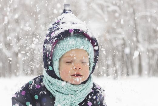 Baby in a winter jumpsuit rejoices in the first snow