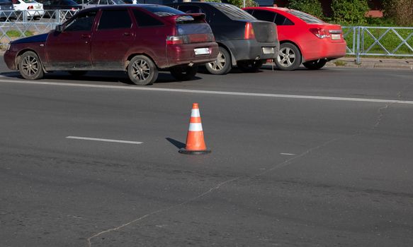 an orange traffic cone on the road indicates the path, road works, detour of a dangerous section of road, roadway repairs.