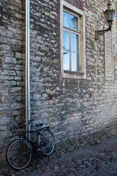 Black vintage bike at the stone wall of the old house