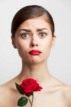 Brunette with bare Roses in the hands of a sad expression shoulders spa treatments light background