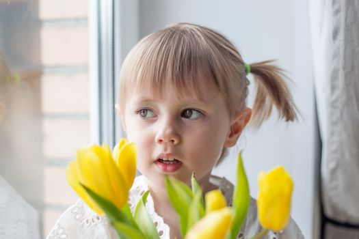  A Portrait of a beautiful little girl with a bouquet of yellow tulips flowers by 8th march international womens day