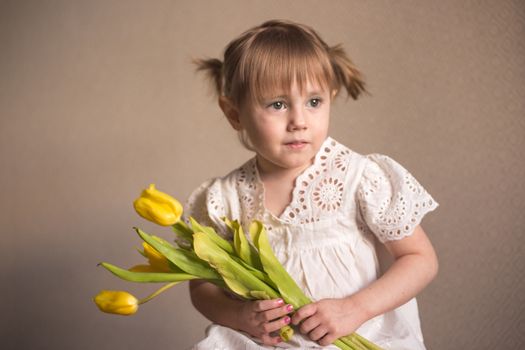  A Portrait of a beautiful little girl with a bouquet of yellow tulips flowers by 8th march international womens day