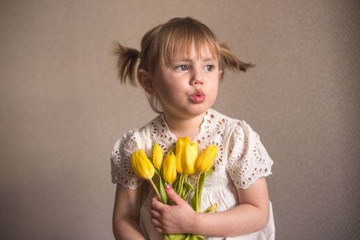  A Portrait of a beautiful little girl with a bouquet of yellow tulips flowers by 8th march international womens day