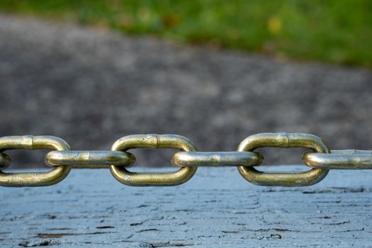 The links of a taut steel chain hover over a wooden surface.