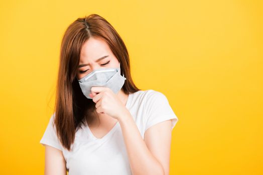 Asian happy portrait beautiful cute young woman teen standing wear t-shirt cough in mask protection from virus epidemic or air pollution isolated, studio shot on yellow background with copy space