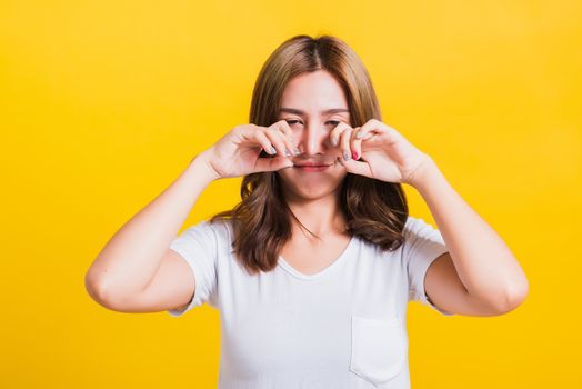 Asian Thai portrait beautiful cute young woman in depressed bad mood her cry wipe tears with fingers, studio shot isolated on yellow background with copy space