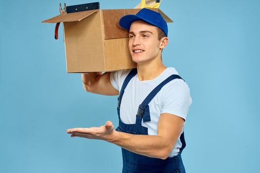 working man in uniform box with tools loader delivery blue background. High quality photo