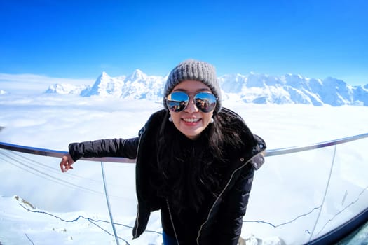 Young Woman Tourist at the Schilthorn in Switzerland with a magnificent panoramic view of the Swiss Skyline. 