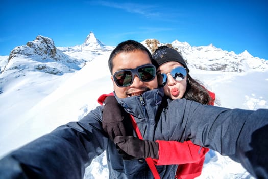 Young Couple Tourists selfie with mobile phone near view of snow mountain Matterhorn, Zermatt, Switzerland