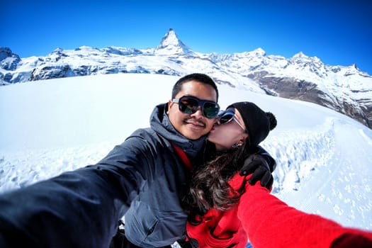 Young Couple Tourists selfie with mobile phone near view of snow mountain Matterhorn, Zermatt, Switzerland