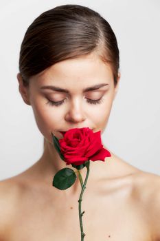 Attractive woman eyes closed sniffing a rose red lips light background