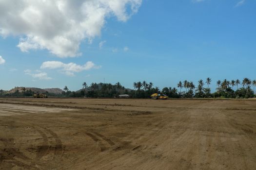 Working machines and heavy equipment adjust the terrain of the race track. Construction of the area and the Moto GP Mandalika racing circuit, West Nusa Tenggara, Lombok, Indonesia. Building a racetrack for motorcycles.