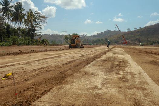 Working machines and heavy equipment adjust the terrain of the race track. Construction of the area and the Moto GP Mandalika racing circuit, West Nusa Tenggara, Lombok, Indonesia. Building a racetrack for motorcycles.