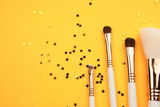 Makeup brushes in different sizes on a yellow background and glitter cropped look. High quality photo