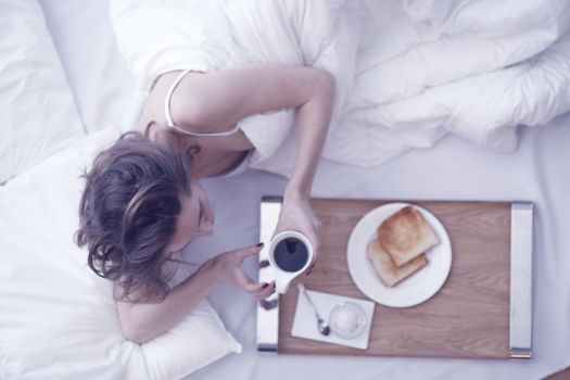 Young woman has a breakfast in the bed top view