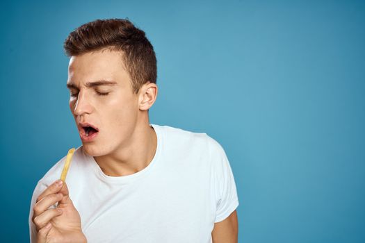 man with fries in cardboard plate calories fast food blue background teen model cropped view. High quality photo