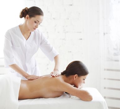 Young attractive woman getting spa treatment massage over white background
