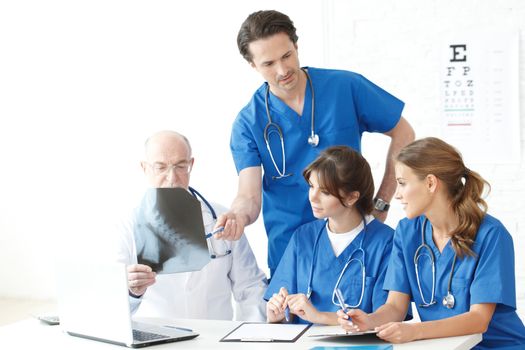 Group of medical doctors and nurses looking at X-ray in office