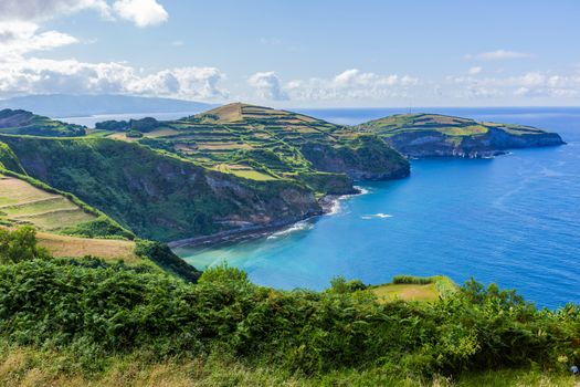 View from the Miradouro de Santa Iria on the island of São Miguel in the Azores. The view shows part of the northern coastline with cliffs and green fields on the clifftop.
