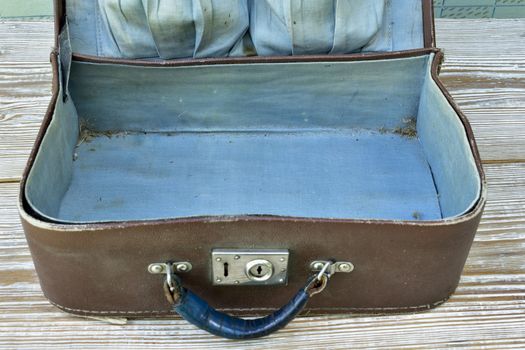 old suitcase lies on a shabby wooden table, open