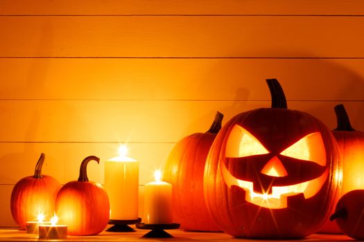 Halloween pumpkin head lanterns and burning candles on wooden background