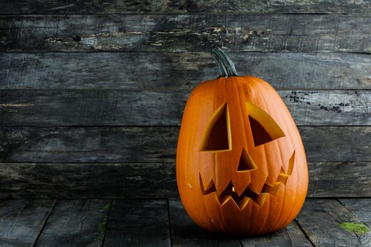 Carved jack-o-lantern halloween pumpkin on wooden background