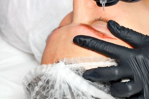 Permanent makeup. Permanent eyebrow tattoo, medical cosmetology. Beautician applies eyebrow tattoo.