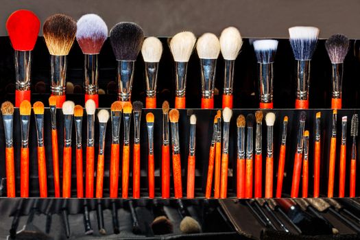 Makeup brushes in an assortment, a large selection, different shapes and sizes, the beauty industry. Dark background, copy space.