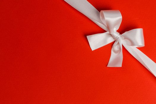 White gift bow on red background holiday gift concept