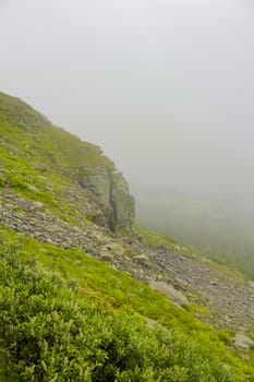 Fog, clouds, rocks and cliffs on Veslehødn Veslehorn mountain in Hemsedal, Norway.