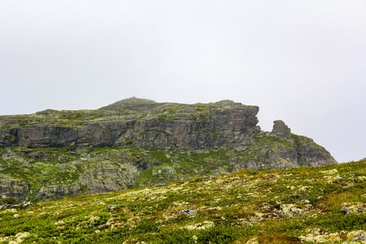 Fog, clouds, rocks and cliffs on peak of Veslehødn Veslehorn mountain in Hemsedal, Norway.