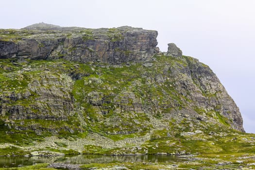 Fog, clouds, rocks and cliffs on peak of Veslehødn Veslehorn mountain in Hemsedal, Norway.