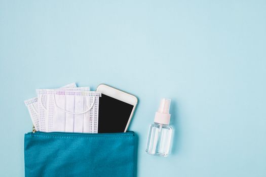 Lady bag with smartphone with hygiene face mask and alcohol gel on blue background for healthcare and new normal or new way of living concept