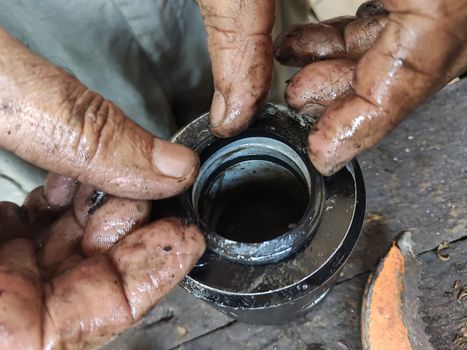 Dirty mechanic's hands work on a small metalwork piece