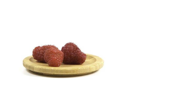 Ripe tasty bright Fresh raspberry in a wicker basket on a cutting board on a white background. High quality photo