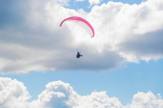 One paraglider is flying in the blue sky against the background of clouds. Paragliding in the sky on a sunny day.