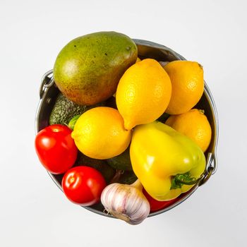 Aluminum bucket with assortment of fresh vegetables on white background.