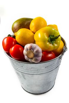 Aluminum bucket with assortment of fresh vegetables on white background.